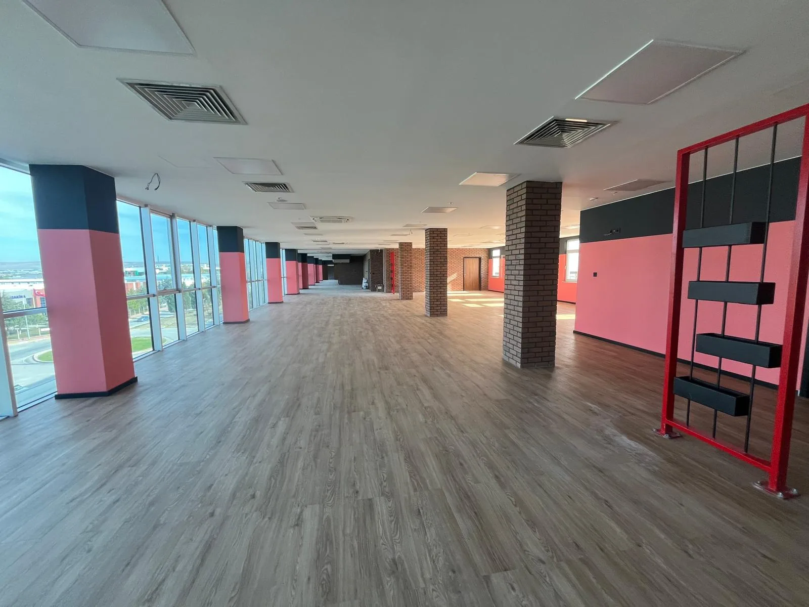 Odunpazarı Eskişehir OSB'deki Alp Havacılık ofisi: mercan pembesi ve antrasit boyalı kolonlar, tuğla desenli kaplama ve ahşap desenli zeminli açık çalışma alanı, 2026